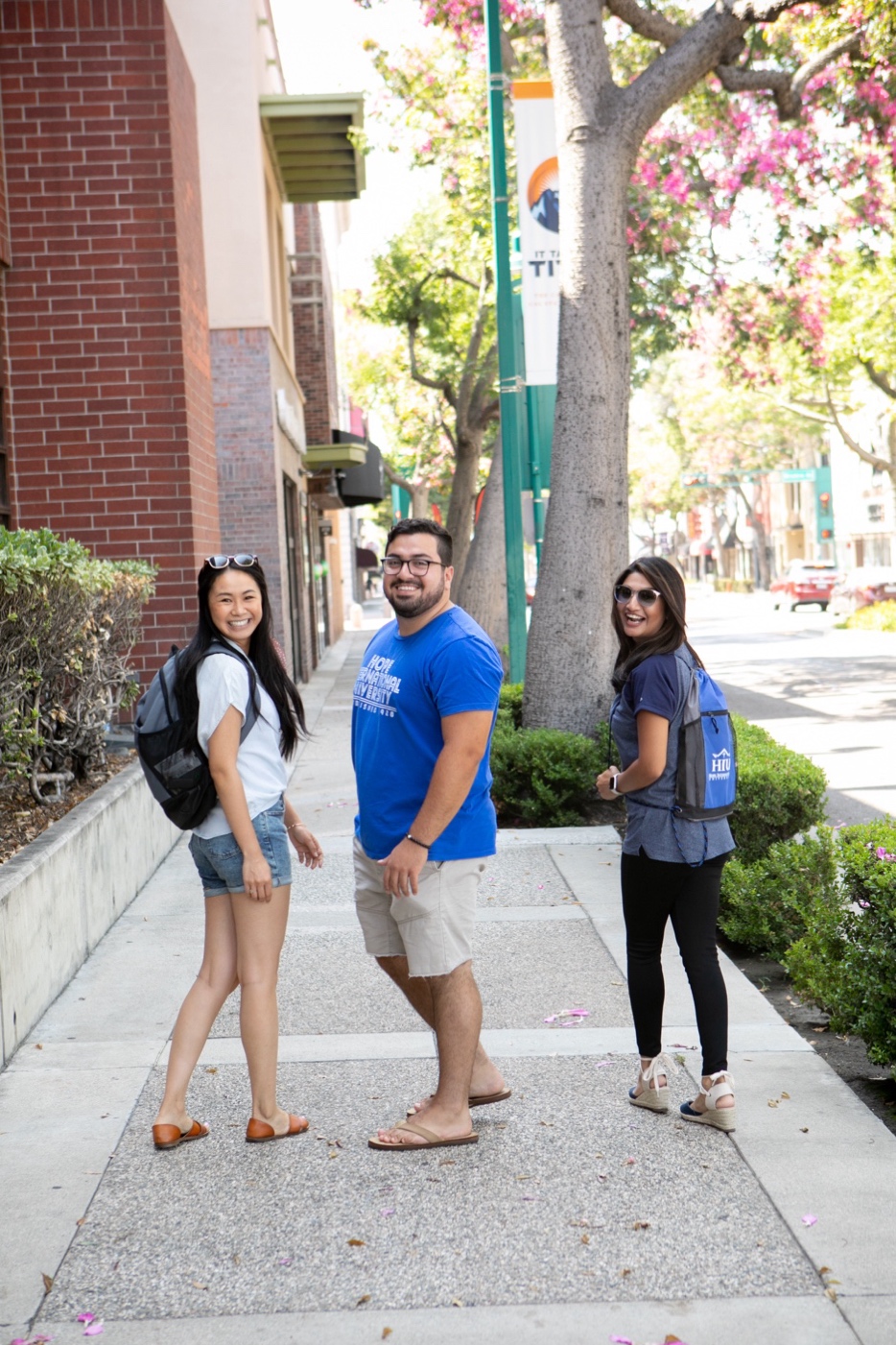 A group of people standing on a sidewalk

Description automatically generated